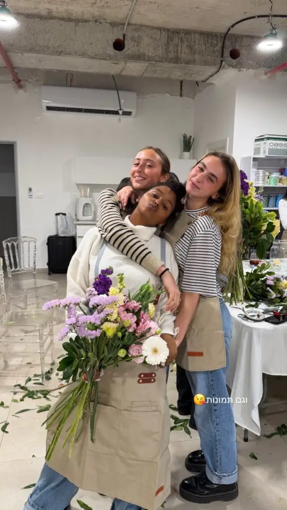משתתפות בסדנת שזירה מחבקות זו את זו עם זר שהכינו
